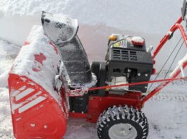 A red snow blower powers through a foot of fresh winter snow for our snow blower maintenance article