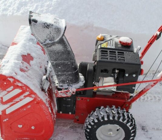 A red snow blower powers through a foot of fresh winter snow for our snow blower maintenance article