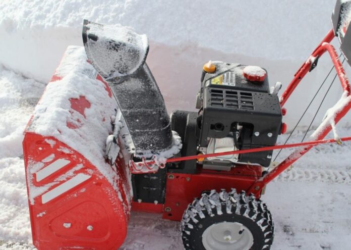 A red snow blower powers through a foot of fresh winter snow for our snow blower maintenance article