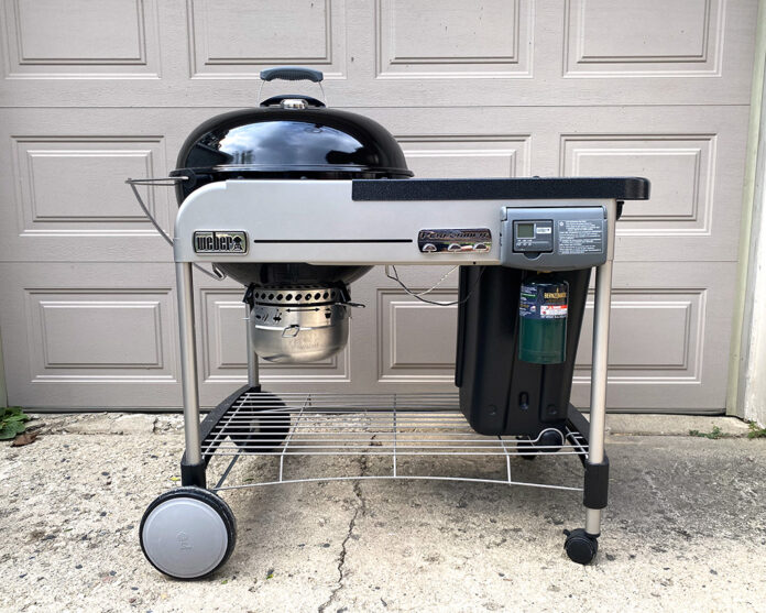Full view of Weber 22 inch Performer Deluxe Charcoal Grill in front of Eric's garage. We reviewed the model with a black lid.