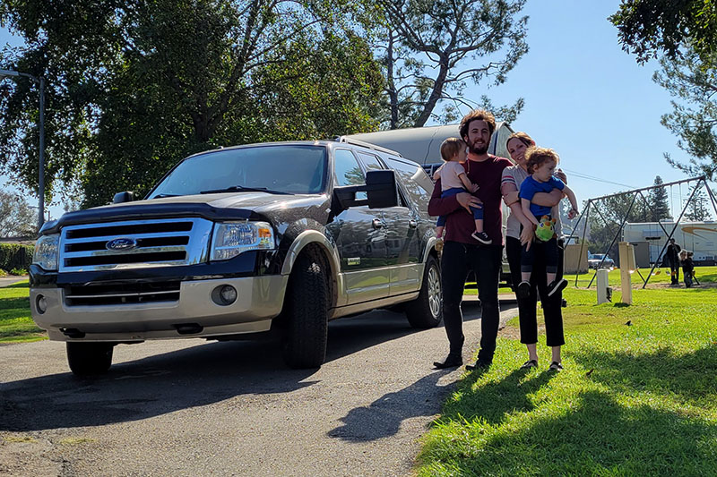 Essentials for Full-time RV Living: family stands in front of their Ford Expedition, which is connected to their travel trailer at Bonelli Bluffs Campground in San Dimas, CA.