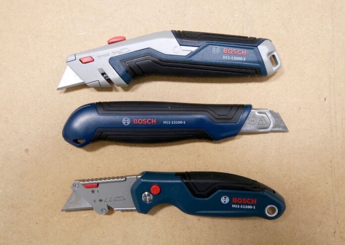 Three Bosch utility knives laid out over a work table. The knives from top to bottom are the BOSCH H11-12100-1 retractable utility knife, the BOSCH H11-13000-1 snap-off utility knife, and the BOSCH H11-11100-1 folding utility knife.