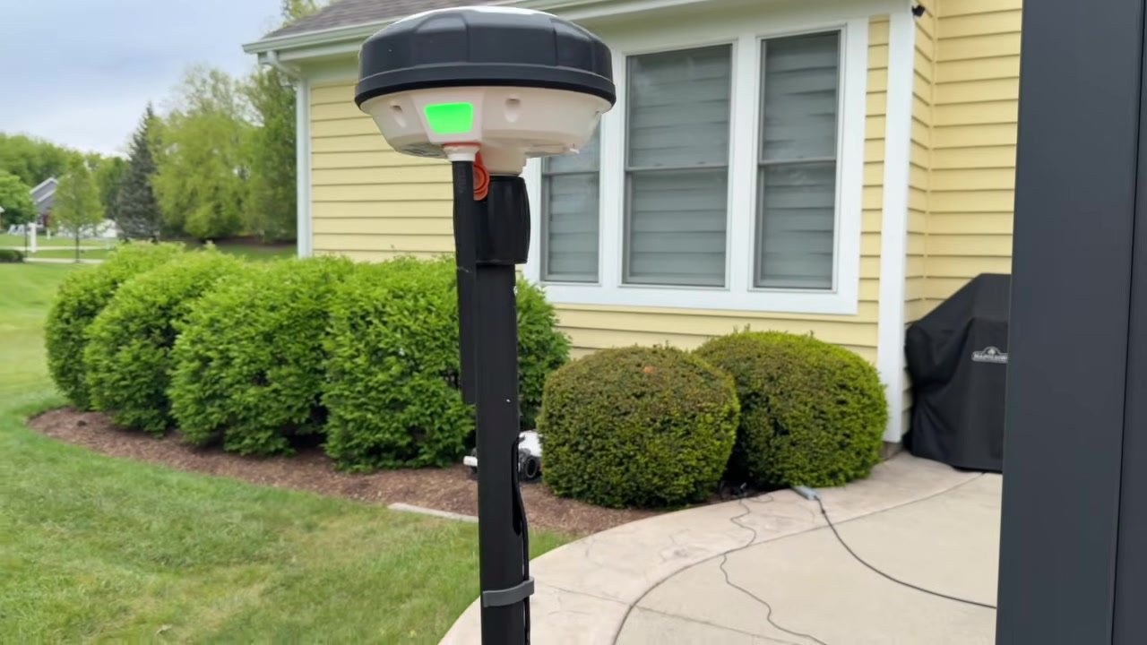 RTK reference station mounted on a pole next to a house