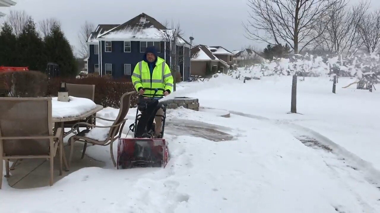 Toro 724 QXE snowblower parked on a snowy patio in front of a house