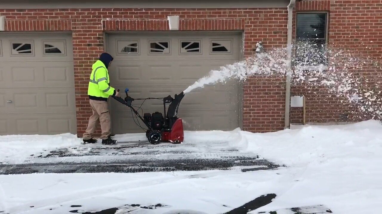 Toro 724 QXE throwing snow in front of a garage