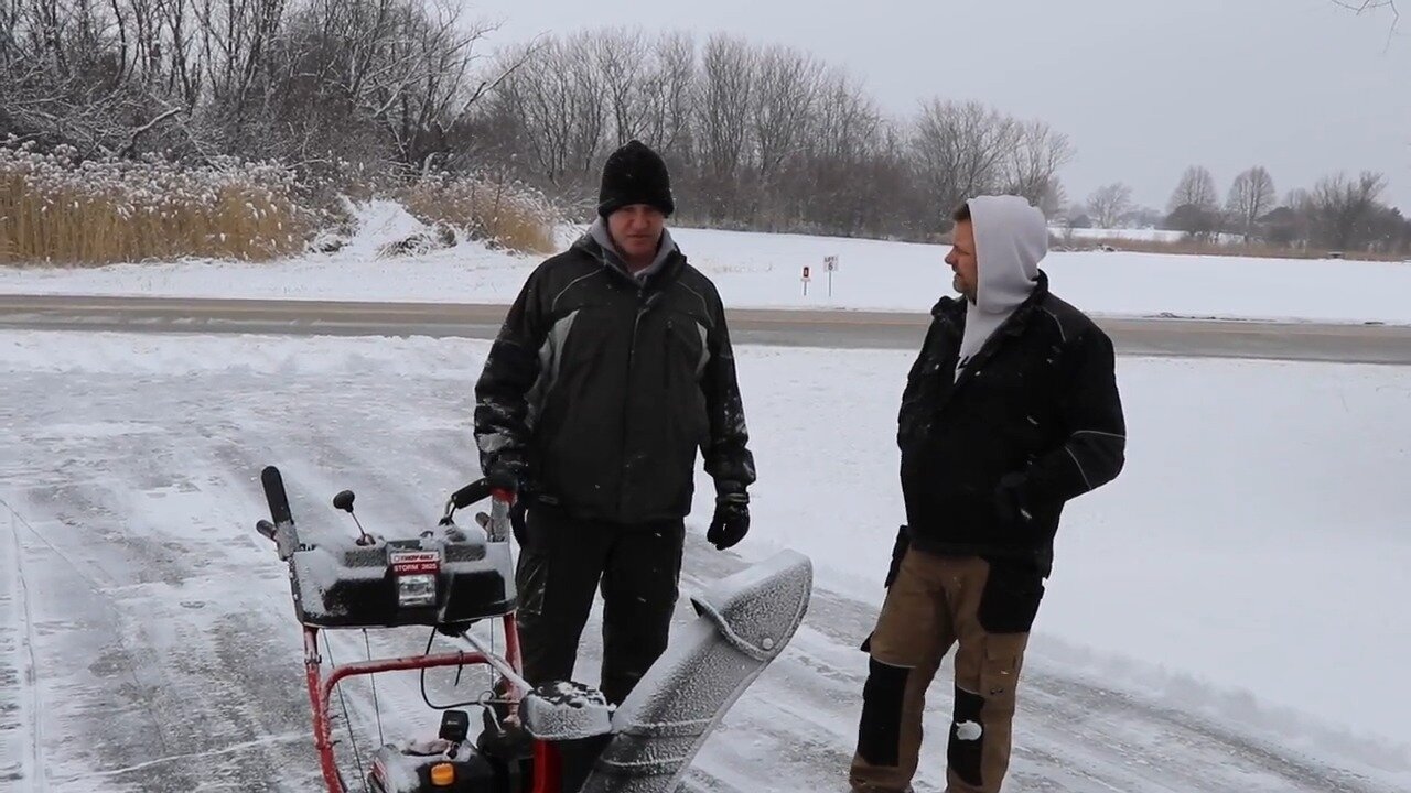 Two-stage Troy Bilt snow thrower on a driveway with the hosts