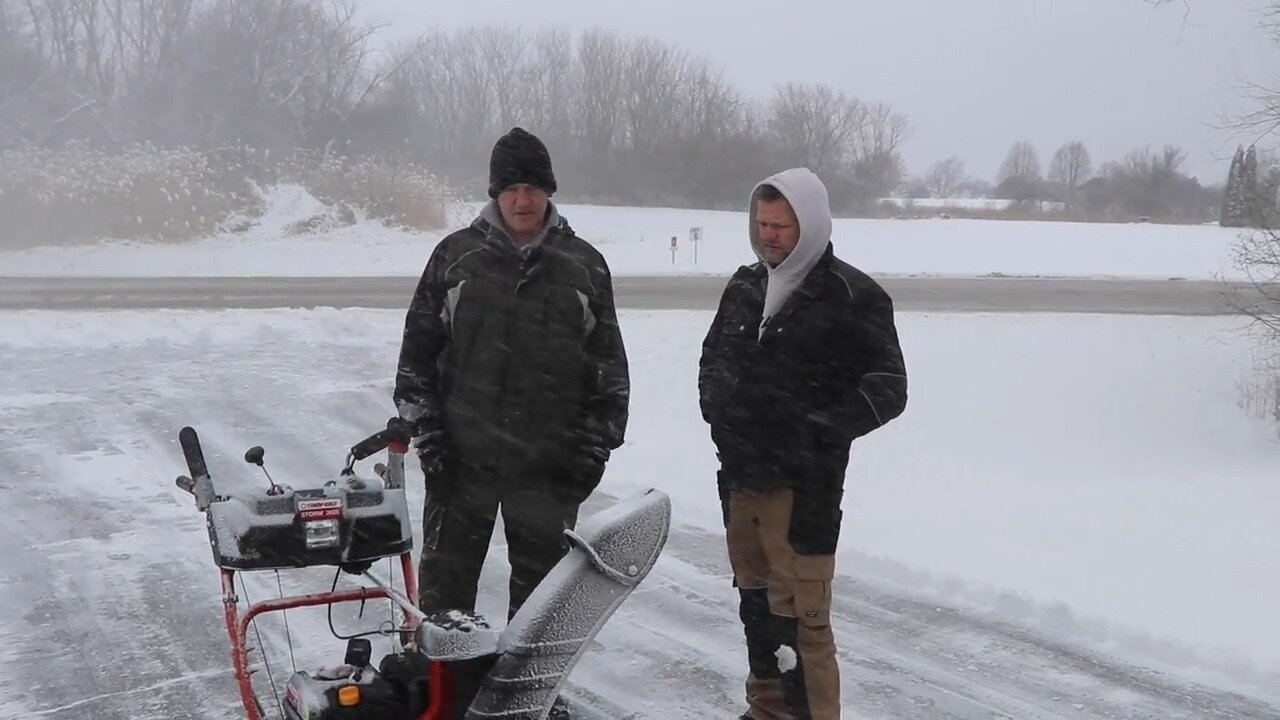 Neighbor discussing the Troy Bilt snow thrower on a driveway